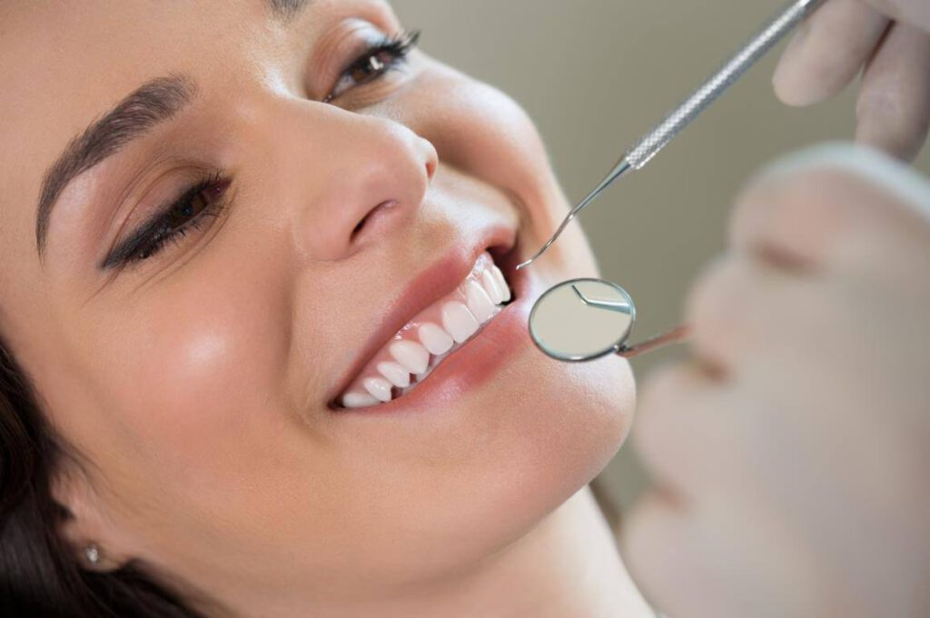 eine Frau lächelt dem Zahnarzt entgegen und zeigt Ihre strahlenden Zähne, Zahnerhalt